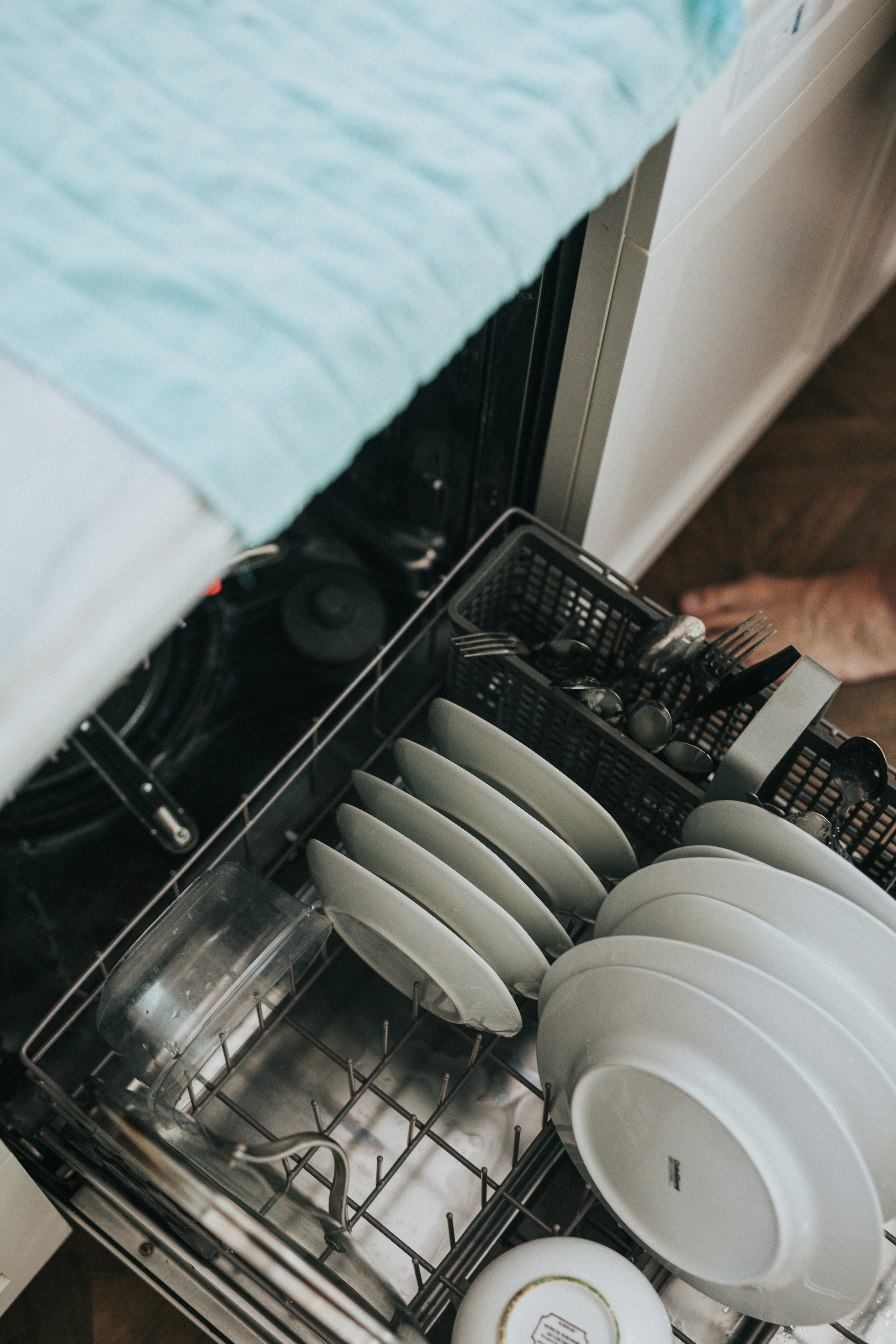 A homeowner in Scottsdale loading dishes into a dishwasher repaired by ACR